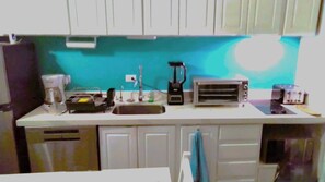 Eine Küche mit Kaffeemaschine, Toaster, Mixer und Spüle.