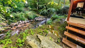 Una cabaña de madera con vistas a un arroyo y follaje circundante.