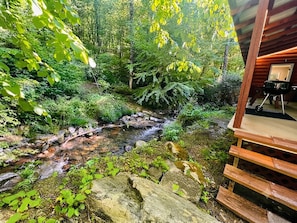 Une cabane en bois offrant une vue sur un ruisseau et la végétation environnante.