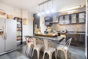 A modern kitchen with a central island, stainless steel appliances, and a tiled backsplash.