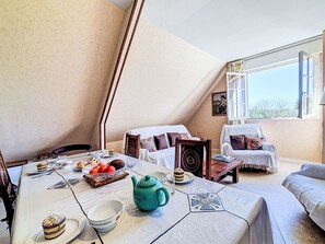 Ein gemütlicher Essbereich mit einem für das Frühstück gedeckten Tisch, inklusive Früchte, Gebäck und einem Teekessel.