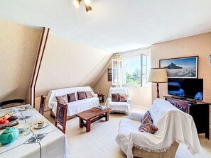 Ein Wohnzimmer mit einer Couch, Sesseln, einem Couchtisch und einem Fernseher.