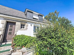 Uma casa de dois andares com fachada de pedra, porta marrom escura e uma pequena janela.