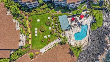 Vue aérienne d’un complexe hôtelier doté d’une piscine, de chaises longues et d’une pelouse bien entretenue.