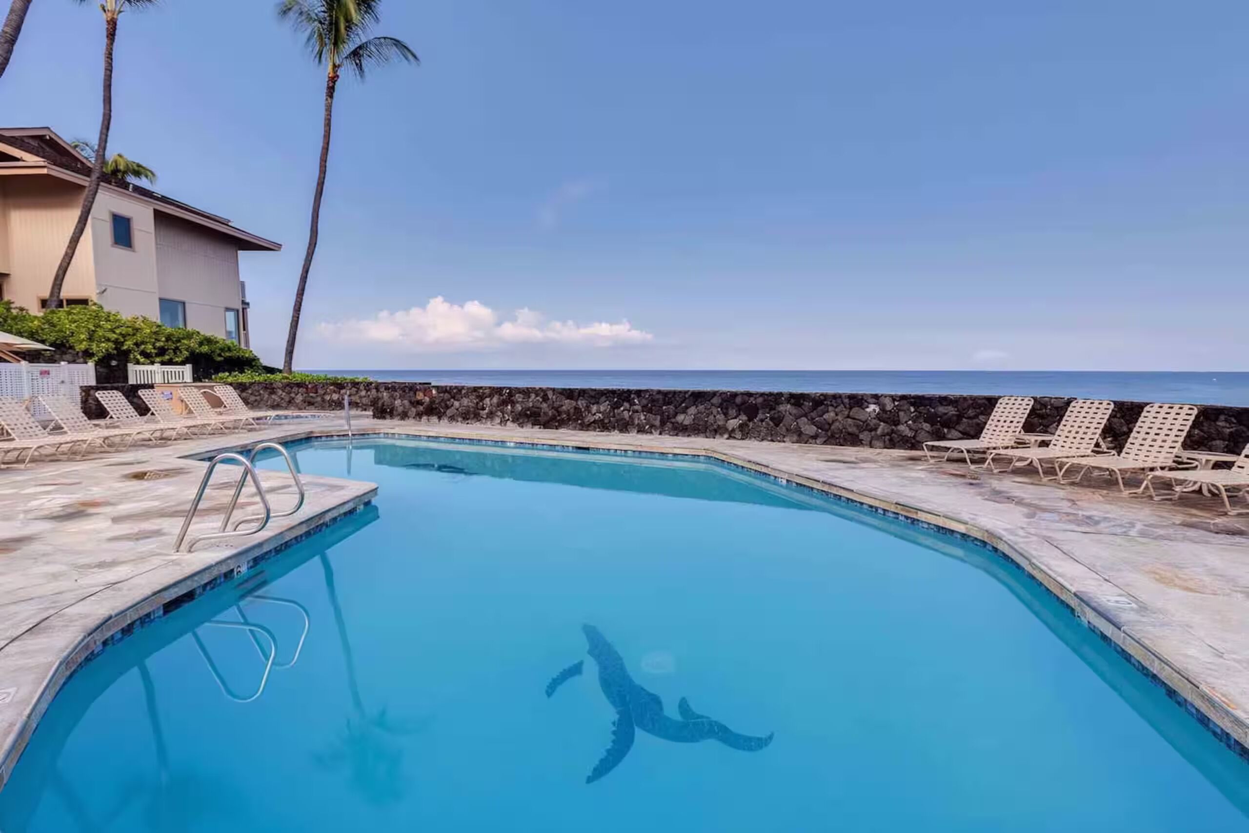 Une piscine avec des chaises longues et vue sur l’océan.