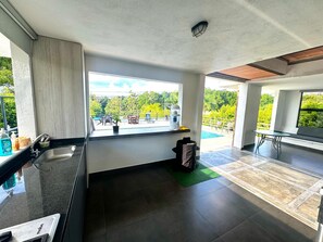 Eine moderne Küche mit großem Fenster, Spüle und Blick auf einen Pool und Grünflächen.