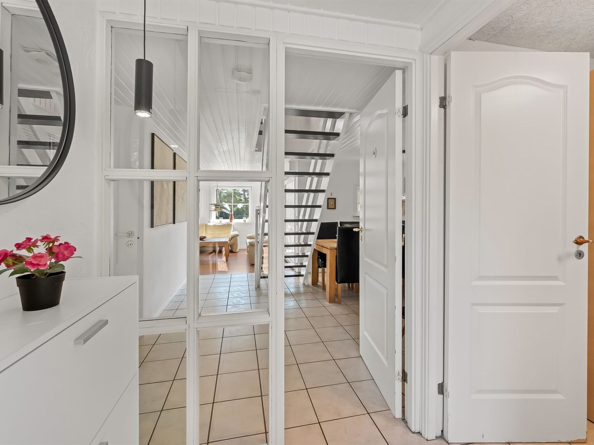 A hallway with a white door, a mirror, and a potted plant.