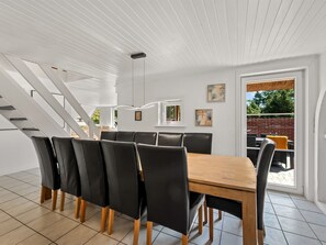 A dining area with a wooden table and black chairs, a staircase, and a view of the outside. - "Eufemia" - 2.8km from the sea by Interhome (Blåvand)