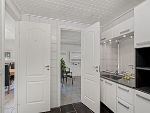 A modern kitchen with white cabinetry, a black countertop, and a large mirror above the sink. - "Eufemia" - 2.8km from the sea by Interhome (Blåvand)