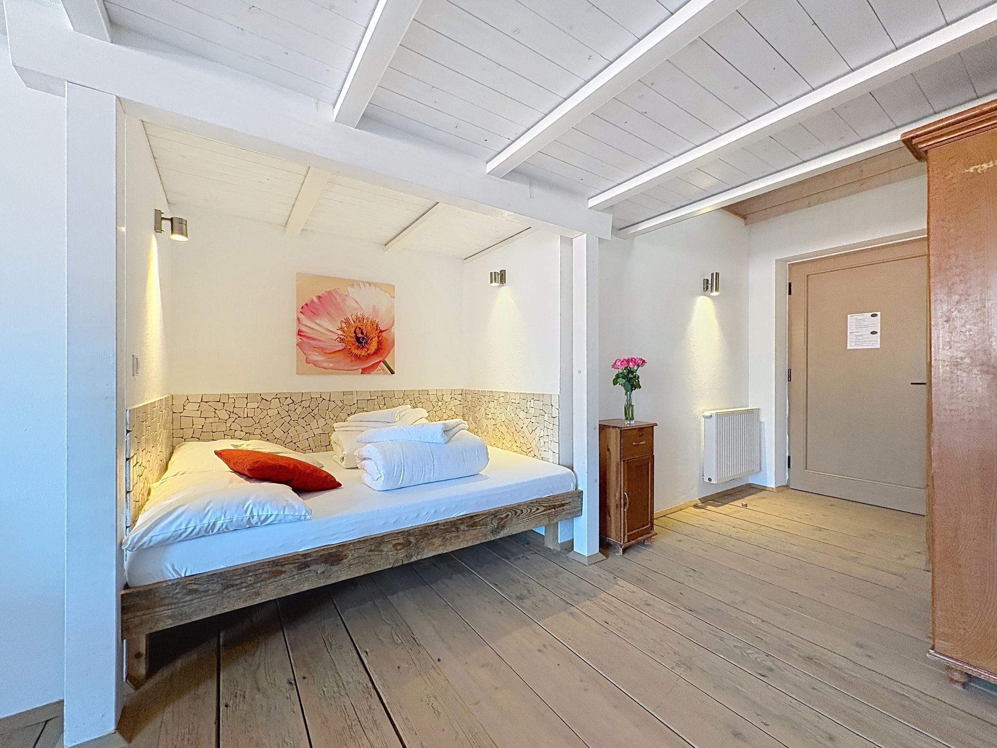 A room with a bed, a wooden cabinet, a radiator, and a door.