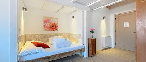 Una habitación con una cama, un armario de madera, un radiador y una puerta.