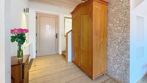 A hallway with wooden flooring, a large wooden wardrobe, and a stone wall. - Edelweiss 2 by Interhome (Kaprun)