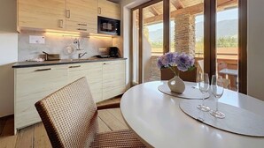Eine moderne Küche mit Holzschränken, einer eingebauten Mikrowelle und einem Essbereich mit Tisch für zwei Personen.