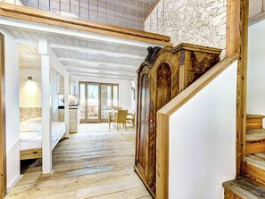Ein geräumiger Raum mit Holzboden, einem großen Holzschrank und einer Treppe, die zu einer oberen Ebene führt.