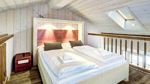 Ein Schlafzimmer mit Holzwänden, einem Bett, Kissen und einem Nachttisch.