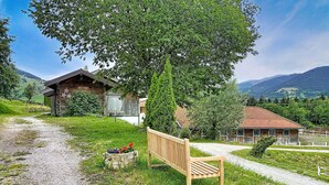 A wooden bench, a gravel path, and a rustic building with a star decoration. - Edelweiss Suite 6 by Interhome (Kaprun)