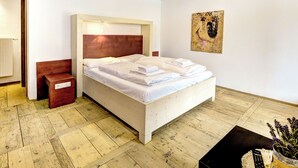 Quarto com cama de madeira, mesa de cabeceira, luminária na parede e uma pintura.