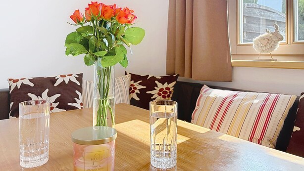 A room with a table, a vase with flowers, and a window with curtains. - Edelweiss Suite 9 by Interhome (Kaprun)