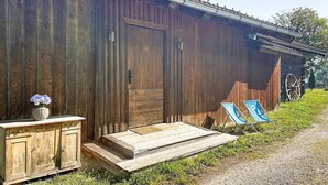 Ein rustikales Holzgebäude mit einem Metalldach, einer Holztür und einer kleinen Veranda mit Stufen zu einer Bank.
