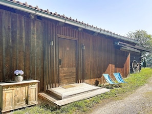 A rustic wooden building with a metal roof, a wooden door, and a small porch with steps leading to a bench. - Sweet Edelweiss 5a by Interhome (Kaprun)