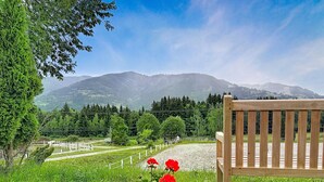 Eine Bank in einem Garten, im Hintergrund eine gebirgige Landschaft.