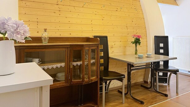 Ein Essbereich mit Holzwand, einem Tisch mit Stühlen und einer Schranke mit Glastüren.