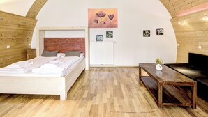 Ein Schlafzimmer mit Holzboden, einem Bett, einem Nachttisch, einer Heizung und einem Bild an der Wand.