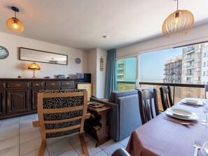 A modern living room with a dining area, large windows, and a view of a building. - Zeewind "close to the beach" by Interhome (Blankenberge)