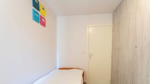 A small, narrow room with a single bed, a wardrobe, and a door leading to another room. - Zeewind "close to the beach" by Interhome (Blankenberge)