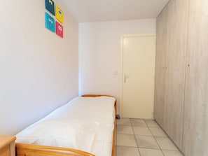 A small, narrow room with a single bed, a wardrobe, and a door leading to another room. - Zeewind "close to the beach" by Interhome (Blankenberge)
