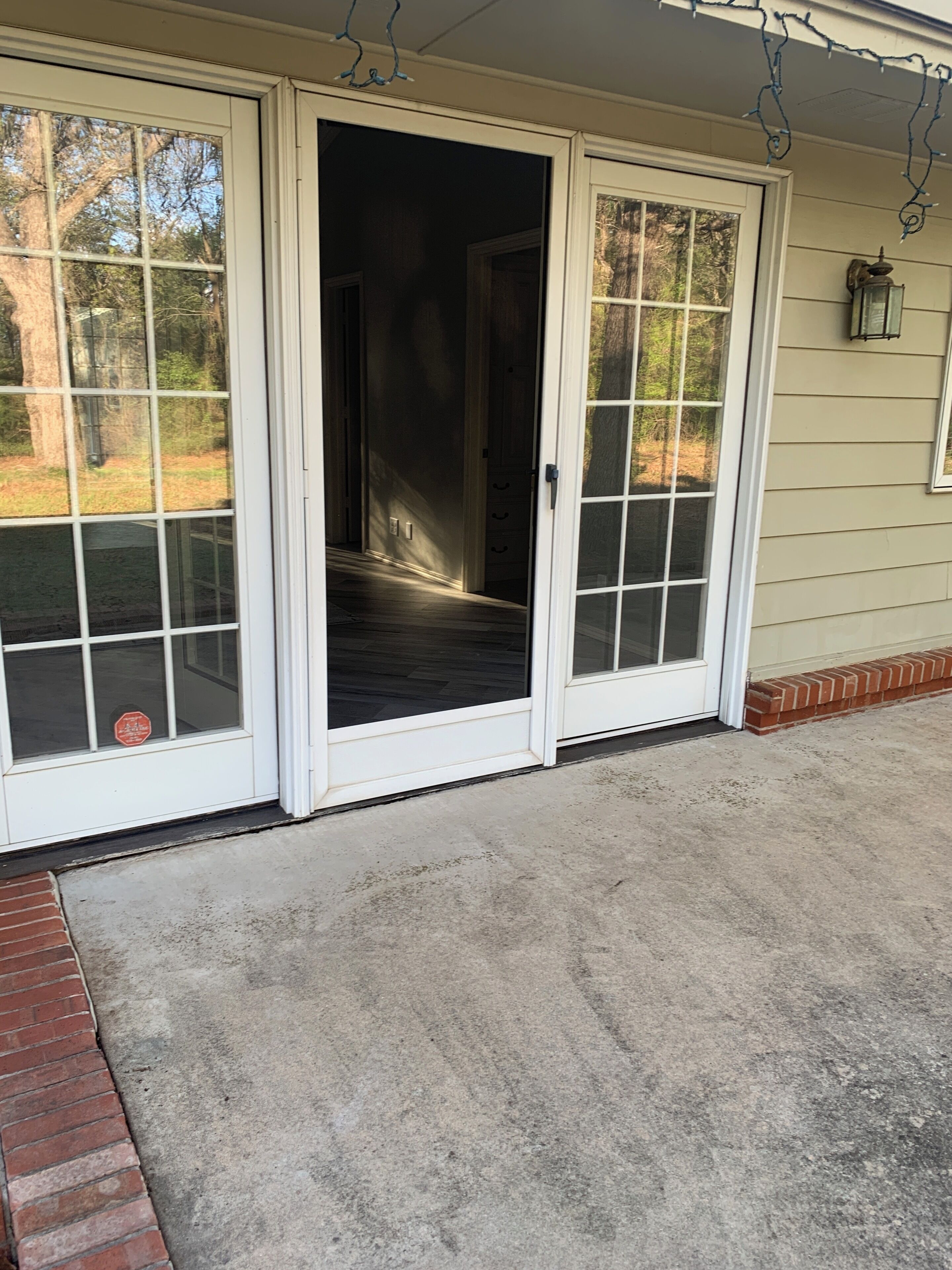 A house with a covered entryway, a brick base, and a concrete floor.