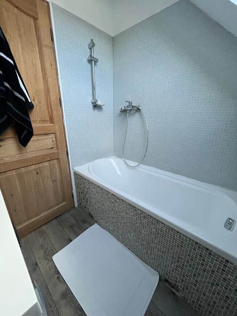 A bathroom with a bathtub, a shower, and a wooden door.