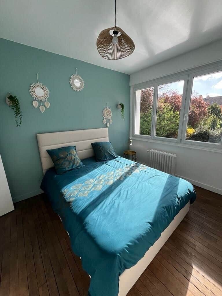 A bedroom with a bed, a window, and wall decorations.
