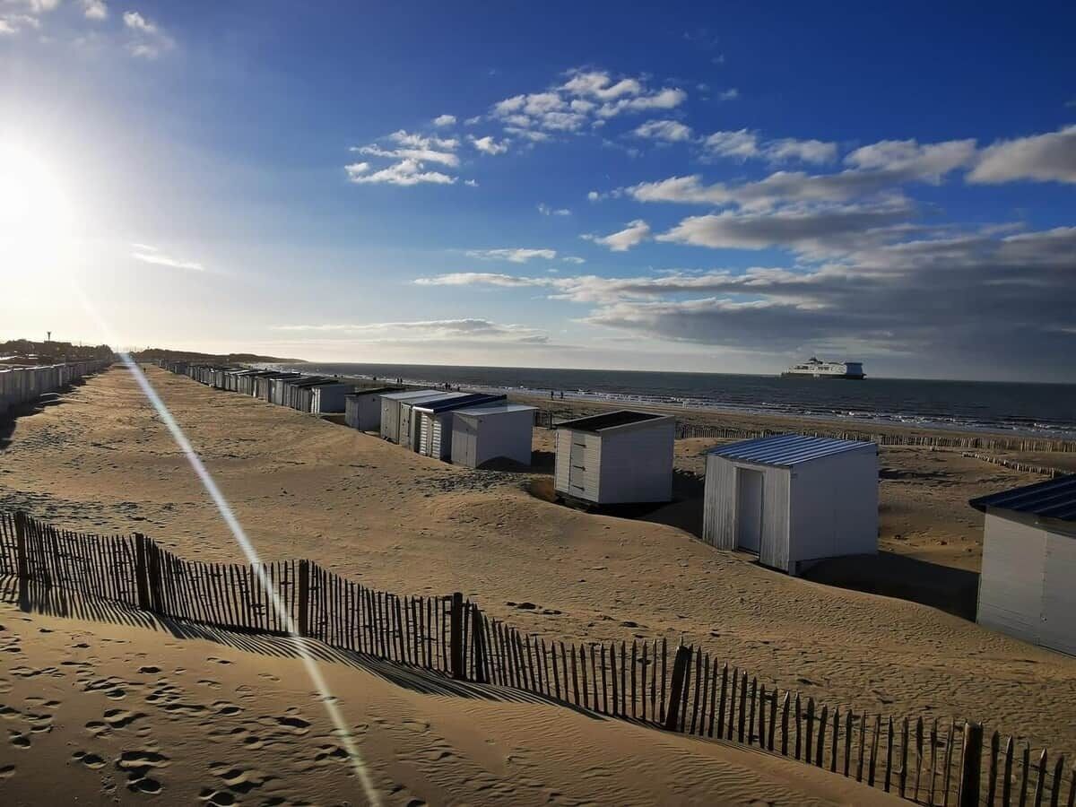 A sandy beach with portable buildings and a wooden fence.