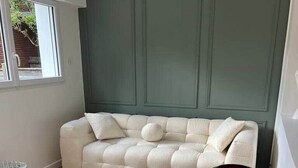 Et værelse med en sofa, to sengeborde, et rundt sofabord og et vindue.