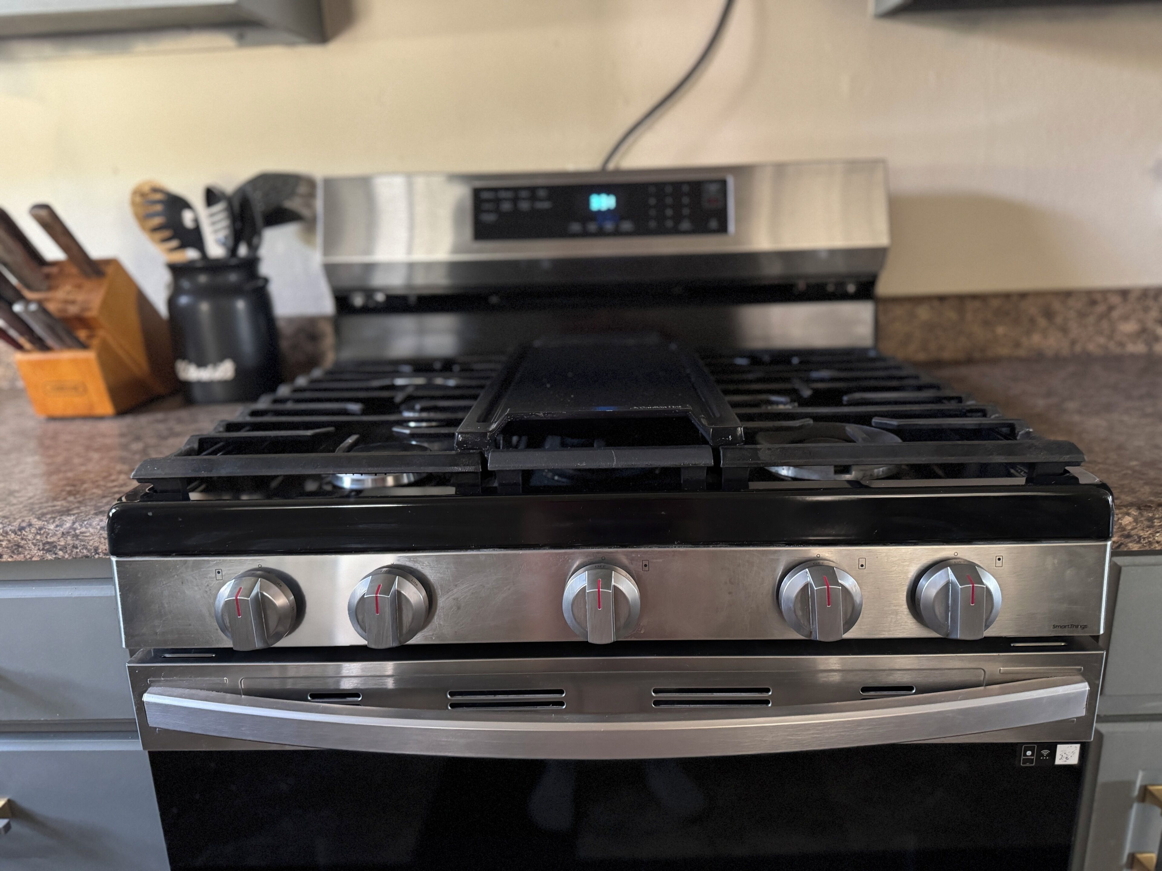 Una cocina con estufa, horno y panel de control digital de acero inoxidable.