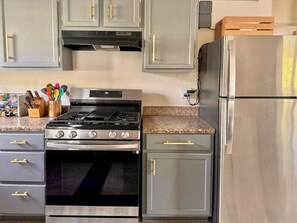 A kitchen with a stainless steel stove, oven, and refrigerator, grey cabinets with gold handles, and a granite countertop. - Lux Modern 3BR • King Bed • SmartTV • MassageChair • Pet Friendly • Near Ft Hood (Killeen)