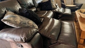 En lædersofa med flere puder og et sofabord.