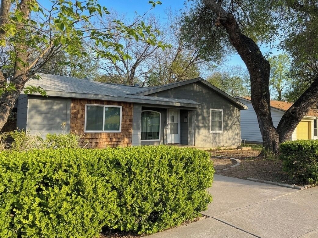 A single-story house with a front porch, a garage, and a well-maintained hedge.