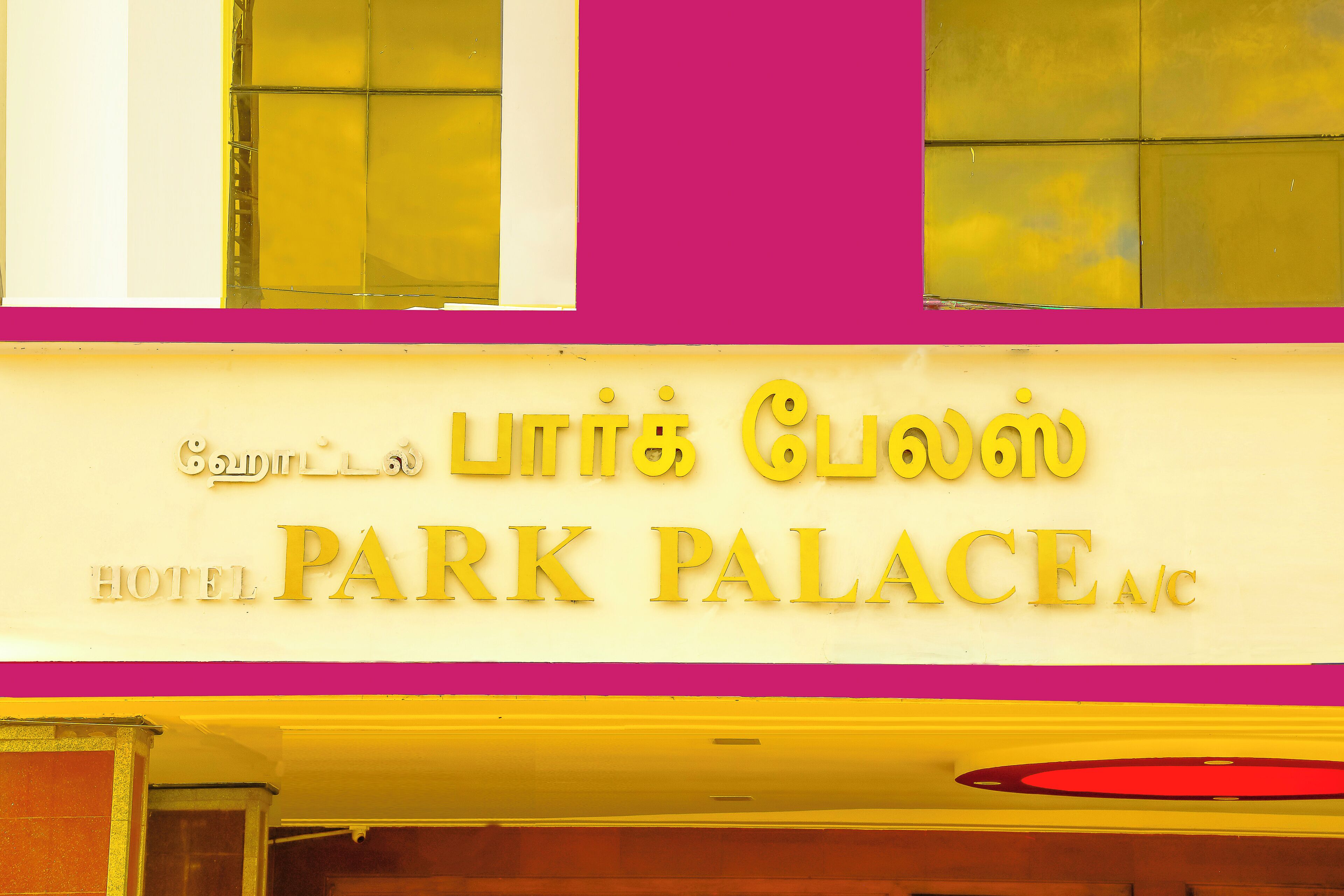 Un letrero de hotel con el nombre 'Park Palace' y una inscripción en escritura tamil en la parte superior.