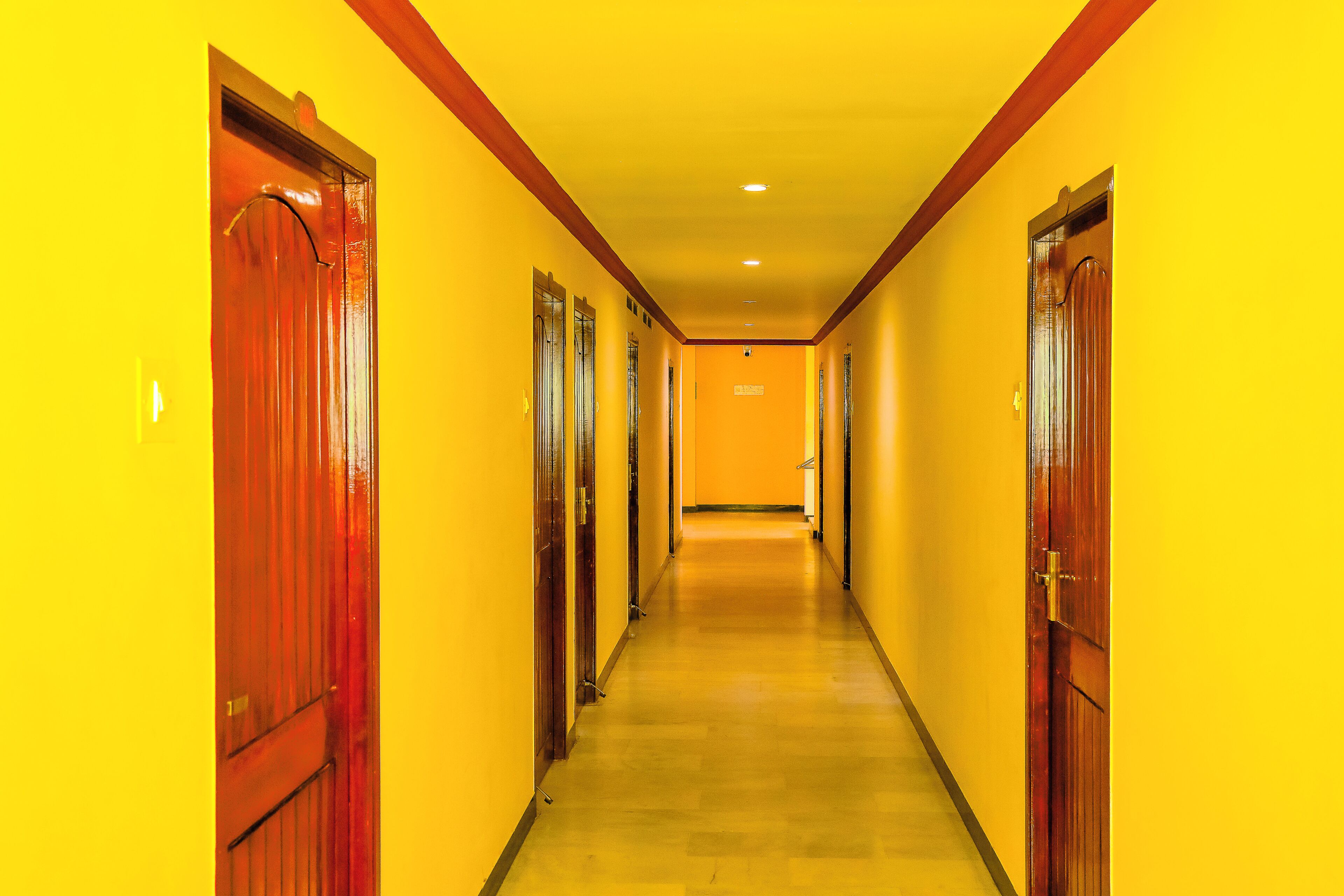 A corridor with doors on both sides, leading to a room with a visible door at the end.