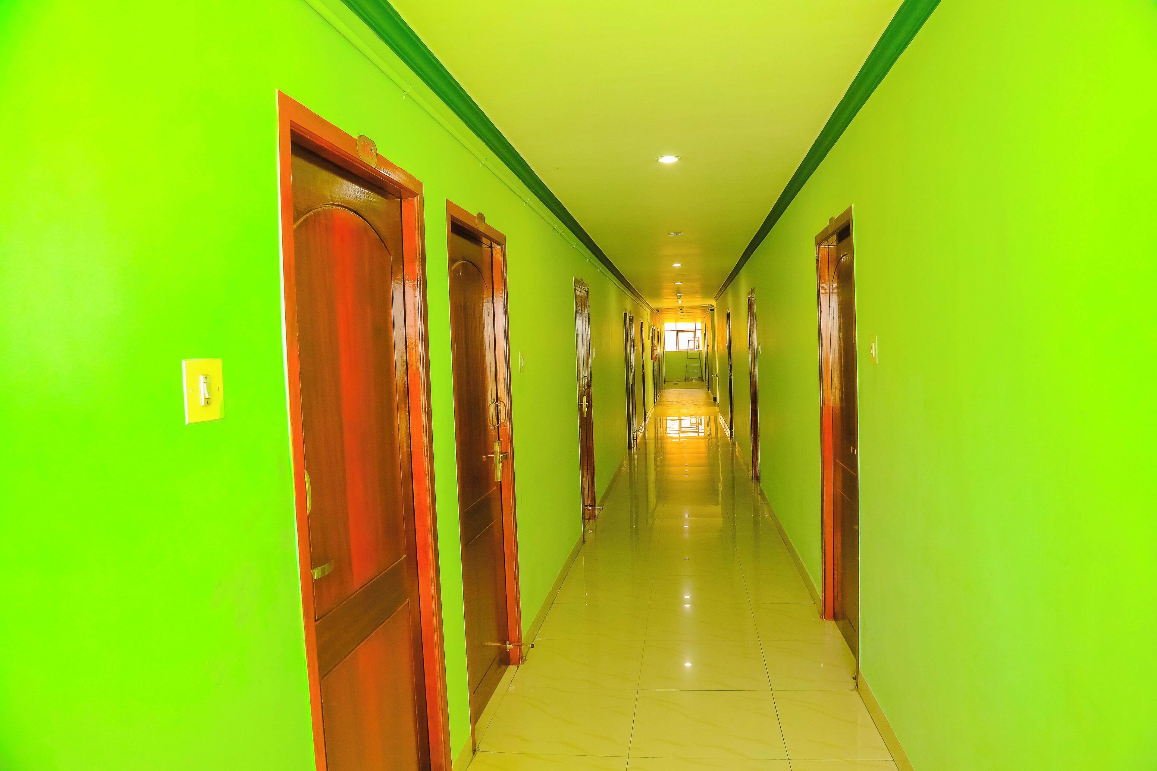 A long, narrow hallway with doors on both sides, leading to a brightly lit room at the end.