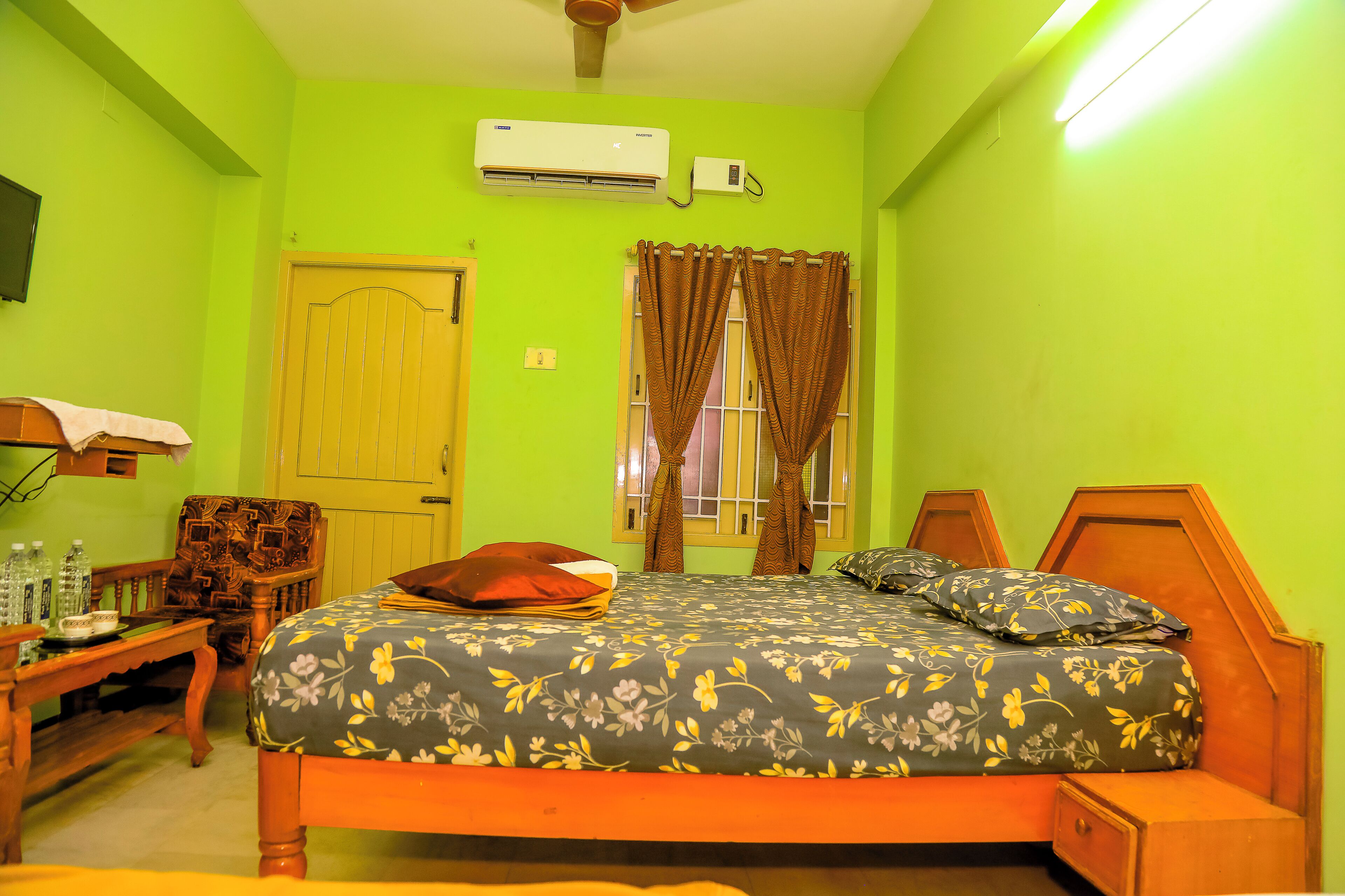 A room with a bed, a desk, a chair, a window with curtains, and an air conditioning unit.