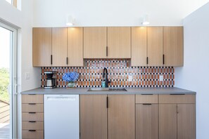Una cocina moderna con armarios de madera, un lavavajillas Bosch, cafetera y salpicadero de azulejos.