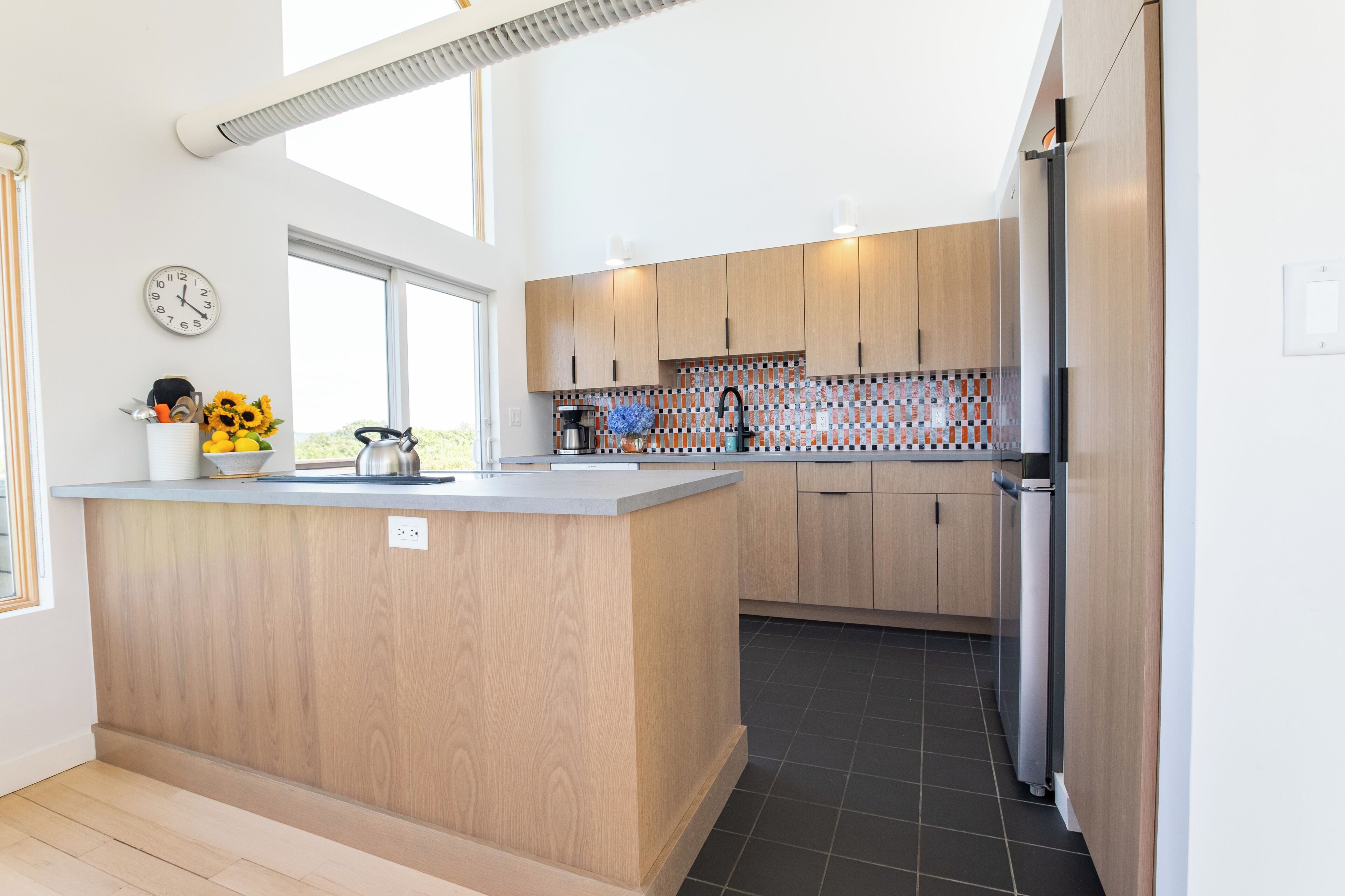 Une cuisine moderne avec des meubles en bois, un îlot central et un four encastré.