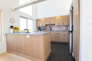 A modern kitchen with wooden cabinets, a central island, and a built-in oven. - Amazing 4-bedroom house with beautiful views in gorgeous Aquinnah (Aquinnah)