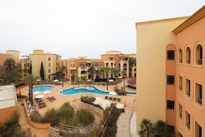 A hotel courtyard with a swimming pool, lounge chairs, and palm trees. - Fun in the Sun! Superior 3 Bedroom with Pool, Golf Views & Marina Walks (Quarteira)