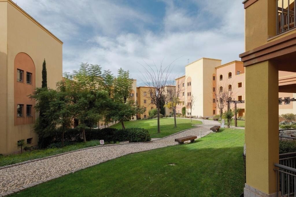 Une cour avec un chemin pavé, des bancs et de la verdure.
