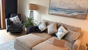 Uma sala de estar com sofá, poltrona e abajur.
