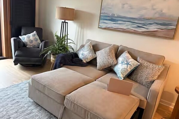 Una sala de estar con sofá, sillón y lámpara.